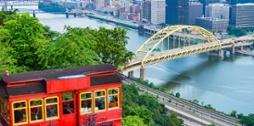 Photo of Pittsburgh's red incline car framing the city's skyline in the distance. 